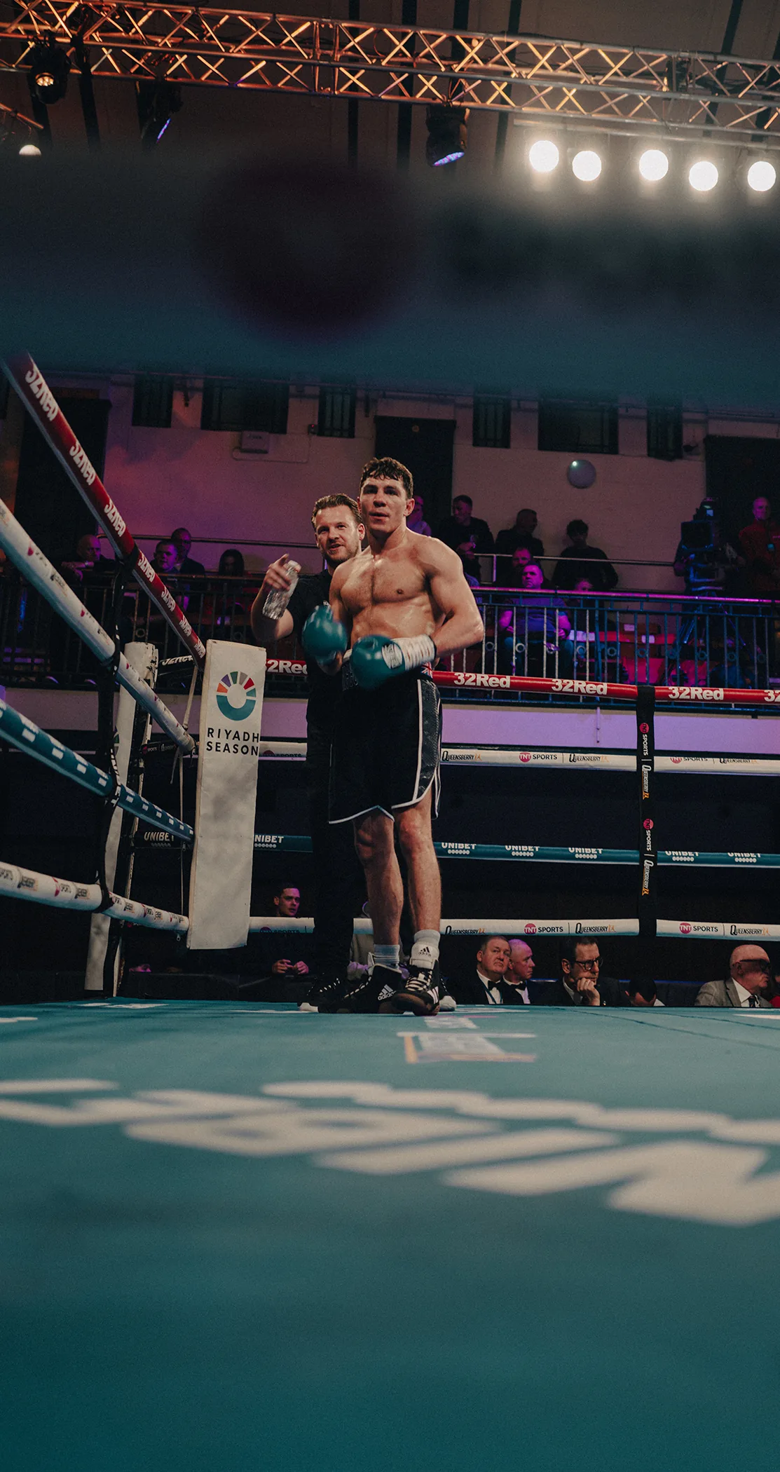 A boxer posing in his corner under the arena lights