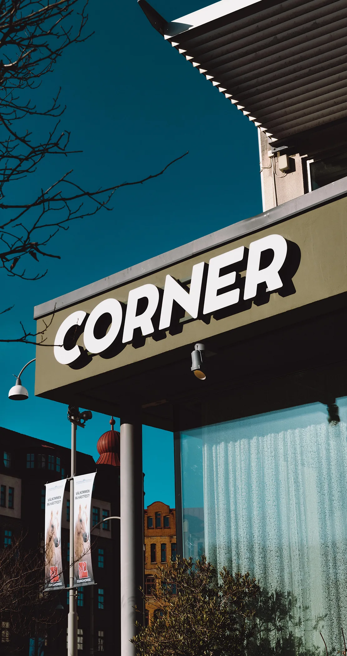 A bold CORNER sign on a building corner against a deep blue sky, Gothenburg