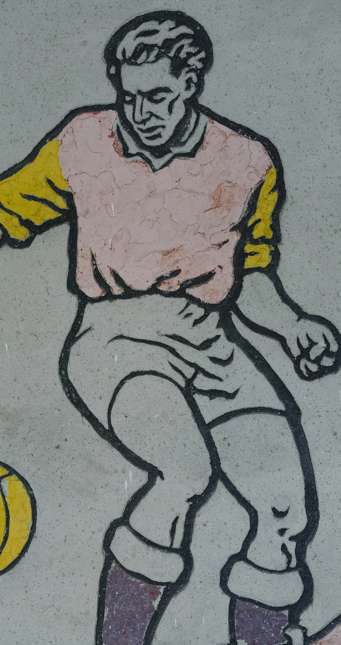 A painted mural of a vintage footballer mid kick