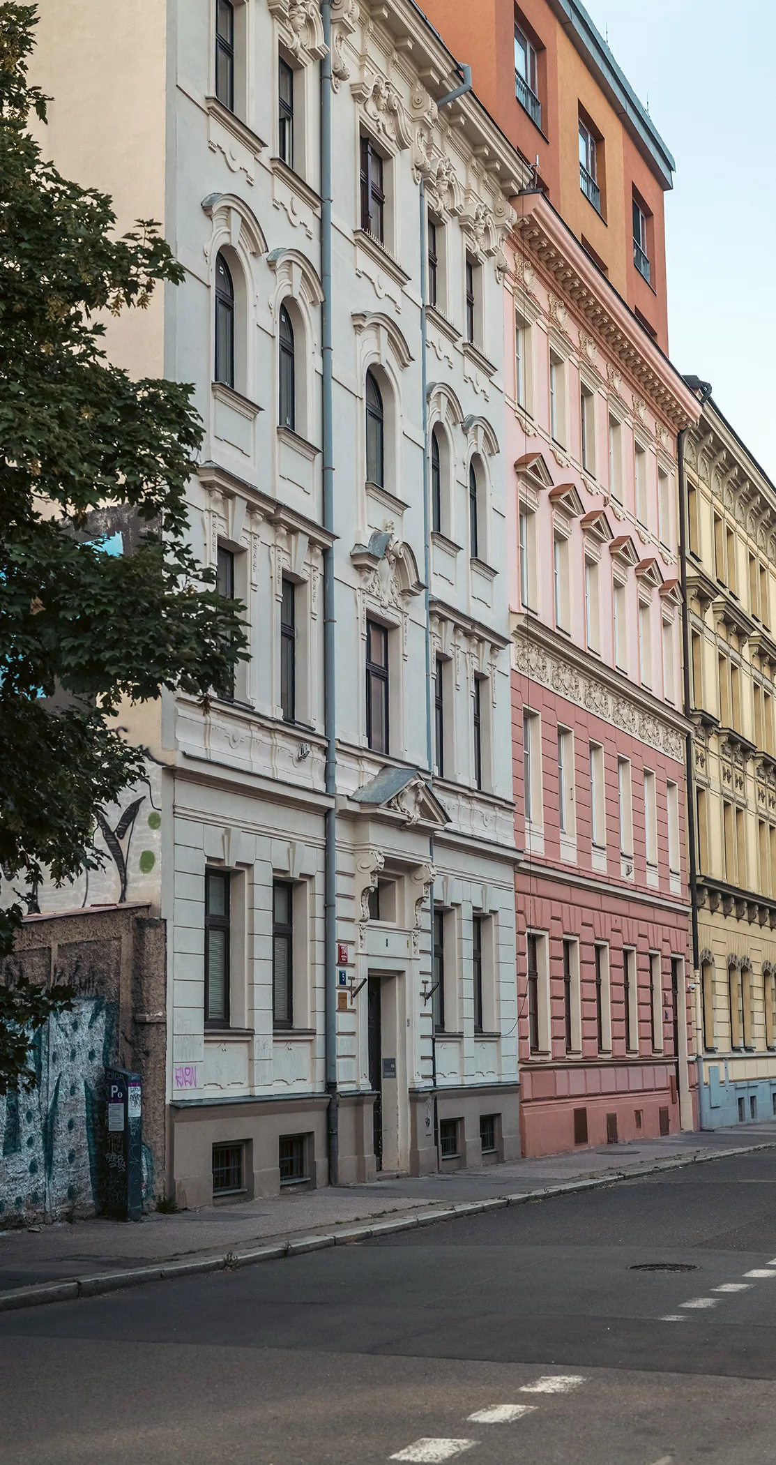 A row of pastel apartment facades along a quiet street, Prague